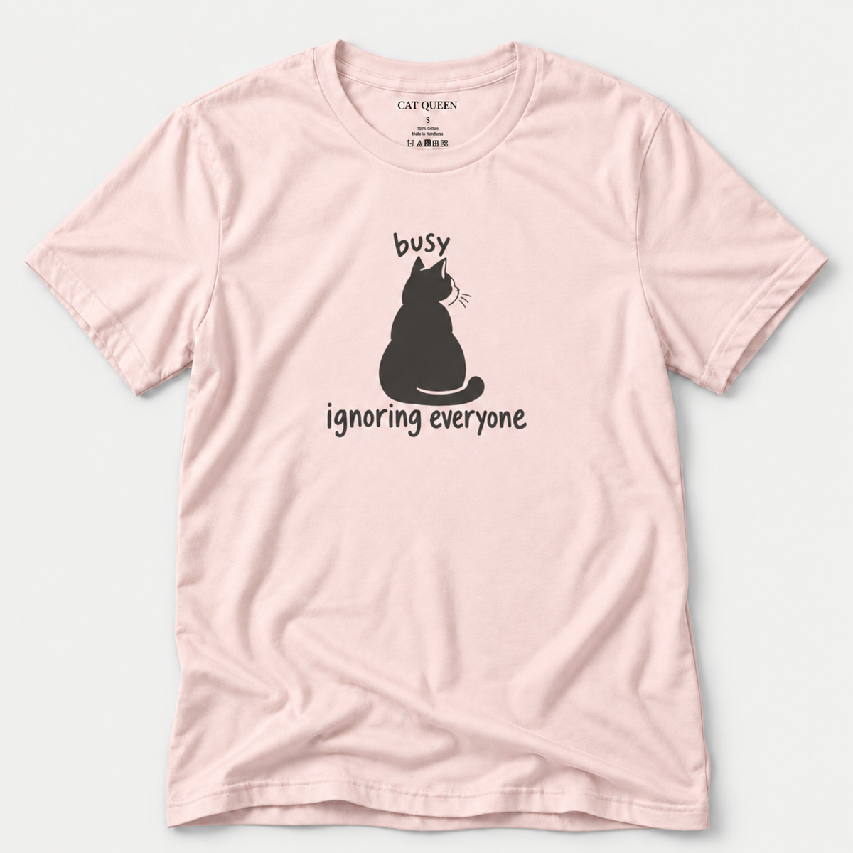 Busy Ignoring Everyone T-Shirt in Soft Pink with black back-facing cat and text design.