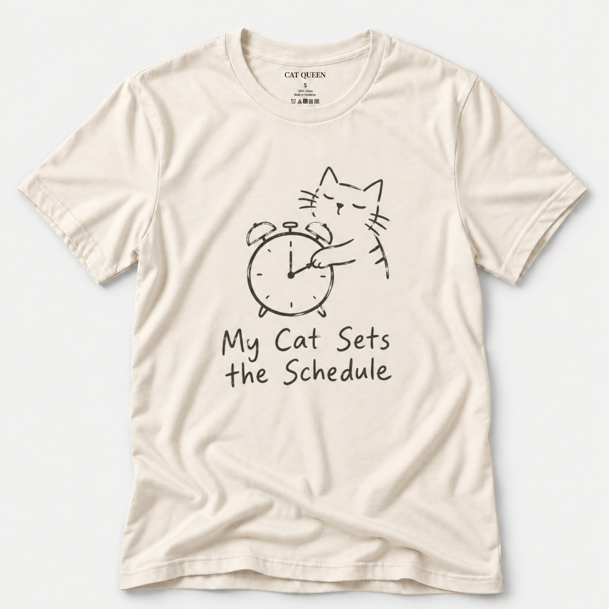 Cat Sets the Schedule T-Shirt in Natural with cat on an alarm clock graphic.