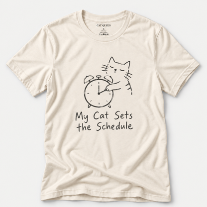 Cat Sets the Schedule T-Shirt in Natural with cat on an alarm clock graphic.
