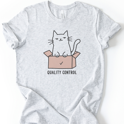 Quality Control Cat T-Shirt in Ash with cat sitting in a pink box graphic.